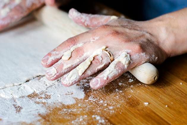 female hands using a rolling pin to pave a dough over a wooden board dirty with flour. female hands using a rolling pin to pave a dough over a wooden board dirty with flour. Preparation of flour-based food such as bread or pizza Copyright: xZoonar.com ValerioxRosatix 15245707