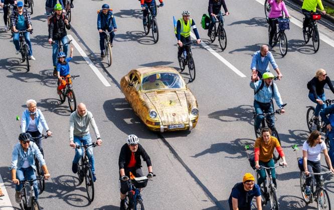 Rad-Sternfahrt des ADFC, Teilstück über die Autobahn A96, München, 23. April 2023 Deutschland, München, 23. April 2023, große Rad-Sternfahrt des ADFC, hier auf der gesperrten Autobahn A 96 bei München-Laim, Teilnehmer mit goldenem Tretauto und Nummernschild Kein Auto, , Fahrraddemo für die Unterstützung des Volksbegehrens Radentscheid Bayern , Motto der Fahrrad-Demo: gemeinsam Radeln für eine bayernweit bessere Radinfrastruktur, Teilstück über die A96 von Sendling bis zur Ausfahrt Blumenau, Verkehr, Fahrrad fahren, Verkehrswende, Umwelt, Klimaschutz, Bayern,