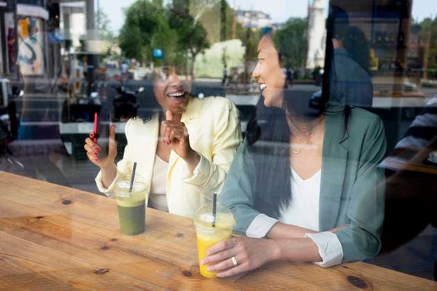 IMAGO Creative, Urban Lifestyle Happy woman talking to friend sitting with juice in cafe seen through window model released, Symbolfoto property released, MMPF00704