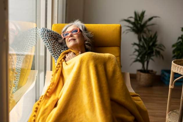 IMAGO Creative: Herbst, Gemütliches Zuhause Thoughtful woman sitting on armchair with yellow blanket model released, Symbolfoto property released, JCCMF10160