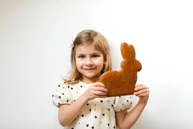 Smiling girl holding gingerbread Easter bunny against white background model released, Symbolfoto, MOMF01010