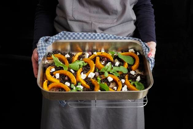 Woman holding baking sheet with roasted pumpkins, common beet, feta cheese and arugula model released, Symbolfoto, EVGF04310