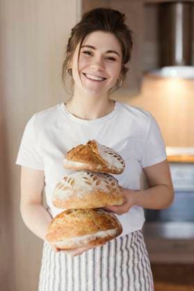 Smiling woman holding freshly baked breads at home model released, Symbolfoto property released, ONAF00481