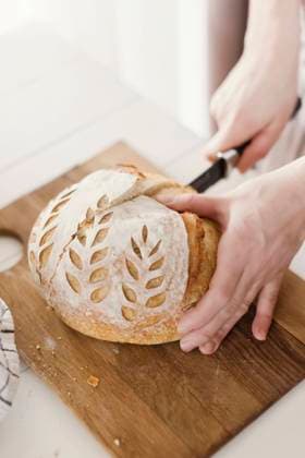 Hands of woman cutting loaf of bread on board model released, Symbolfoto property released, ONAF00486