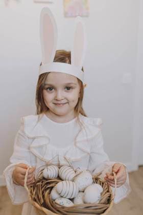 Smiling girl wearing rabbit ears holding basket of Easter eggs at home model released, Symbolfoto property released, VBUF00300