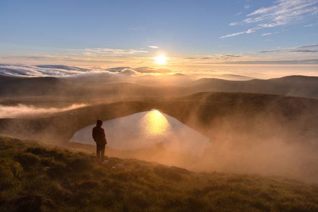 Creative Highlights Symbolbilder Man watching sunrise over heart shaped lake Wicklow, County Wicklow, Ireland CR_SIIZ230324P-1157223-01 ,model released, Symbolfoto