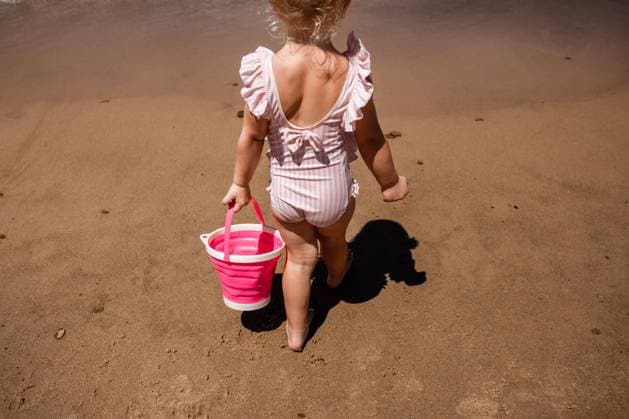 Creative Highlights Symbolbilder Child on sandy beach walking away with pink bucket on summer vac Beverly Shores, Indiana, United States CR_WEKW230425-1176442-01 ,model released, Symbolfoto