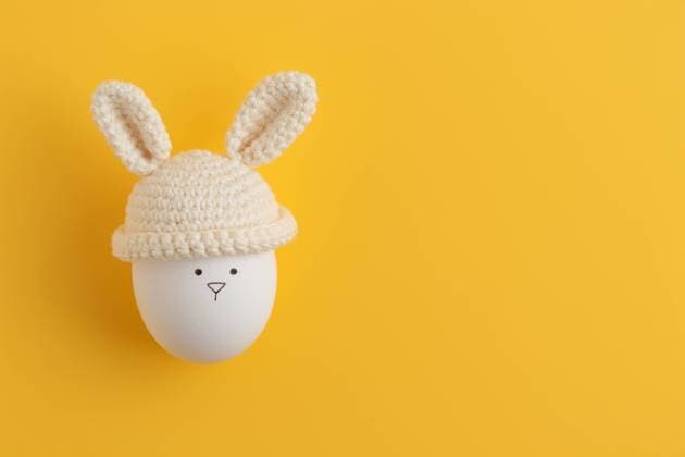 Easter egg in crochet hat with bunny ears on yellow background Finland, Uusimaa, Helsinki R_PWCS23032076-1156457-01