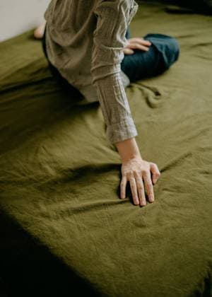 Creative Highlights Symbolbilder Hand of a woman sitting on a bed with green sheets Bangkok, Bangkok, Thailand R_VCXS230317F-1155108-01 ,model released, Symbolfoto