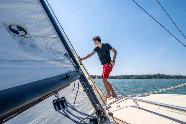 Junger Mann beim Segeln auf einem Segelboot, Ammersee, Bayern, Deutschland, Europa