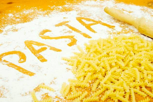 On a wooden table lie scattered about the pasta and flour. On flour text Pasta Copyright: xAlaxCharnyshovax xDesignxPicsx , 30648415 Copyright: PaulxBolotovx xDesignxPics 30648415