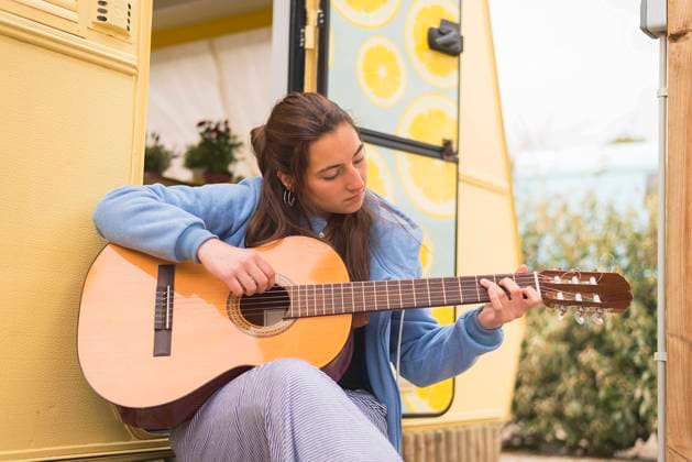Young woman playing guitar at a campsite. Barcelona, Catalonia, Spain CR_RAFE230316-1148445-01 ,model released, Symbolfoto