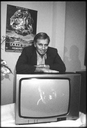 Charlton HESTON . Goldfieber . Pressegespräch + Filmpremiere 15. April 1983, München 5. April 2008: Der Filmschauspieler Charlton Heston stirbt 84-jährig in seinem Haus in Beverly Hills. Der Darsteller von Figuren wie Moses, Judah, Michelangelo oder El Cid erhielt 1959 einen Oscar als bester Hauptdarsteller in Ben Hur und war neben seiner Hollywood-Karriere aktiv als Waffen-Lobbyist tätig. Bild: Oscar-Preisträger (Ben Hur) Charlton HESTON vor dem Filmplakat Goldfieber auf einem Fernsehgerät lehnend, der ein Standbild aus dem Film zeigt Wien Austria *** Charlton HESTON Gold Fever press conference film premiere 15 April 1983, Munich 5 April 2008 The film actor Charlton Heston dies at the age of 84 in his home in Z101000151_020523_01jpeg