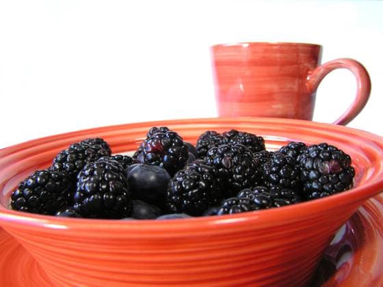 mixed blueberries and blackberries in a bowl on a plate on a black placemat, with cup faded in background Copyright: xChristyxThompsonx xDesignxPicsx , 30784790 Copyright: ChristyxThompsonx xDesignxPics 30784790