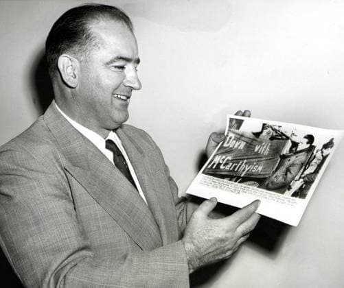 Arkiv 19540129 - Senator Joseph R McCarthy tittar pa ett UPI-foto av kommunisten Andrew Condron framför en bil med banderollen Down with McCarthyism . USA x450x *** Archive 19540129 Senator Joseph R McCarthy looks at a UPI photo of communist Andrew Condron in front of a car with the banner Down with McCarthyism USA x450x  Copyright: xUPIx