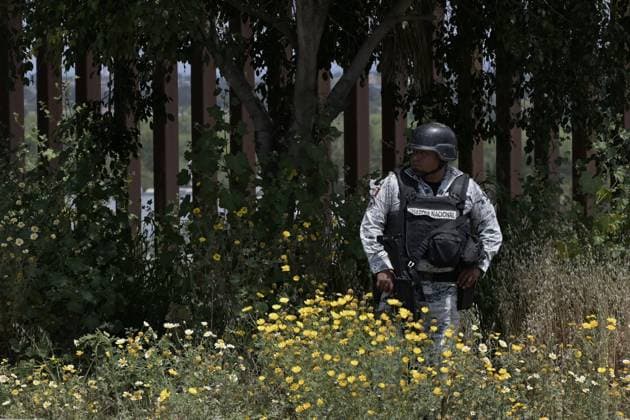 A member of the Mexican National Guard patrols the area where migrants have been stuck between the primary and secondary fencing at the Tijuana-San Diego border for over a week, as many of the migrants are waiting and hoping to be allowed to immigrate to the U.S. more easily after the Title-42 deportation order expires on May 11, as seen from Tijuana, Mexico on Thursday, May 11, 2023.  TIJ2023051103 CarlosxMoreno