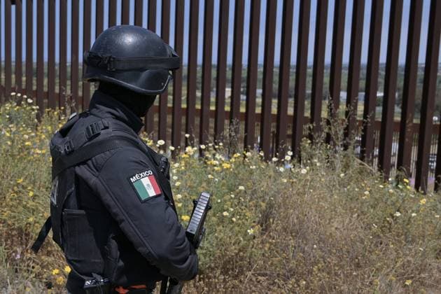 A member of the Mexican National Guard patrols the area where migrants have been stuck between the primary and secondary fencing at the Tijuana-San Diego border for over a week, waiting and hoping to be allowed to immigrate to the U.S. more easily after the Title-42 deportation order expires on May 11, as seen from Tijuana, Mexico on Thursday, May 11, 2023.  TIJ2023051110 CarlosxMoreno