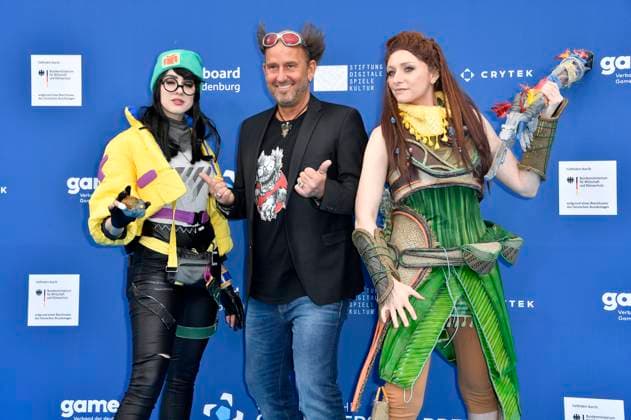 Tom Lehel mit den Cosplayern Killjoy und Aloy bei der Verleihung des Deutschen Computerspielpreises 2023 im Spindler & Klatt. Berlin, 11.05.2023