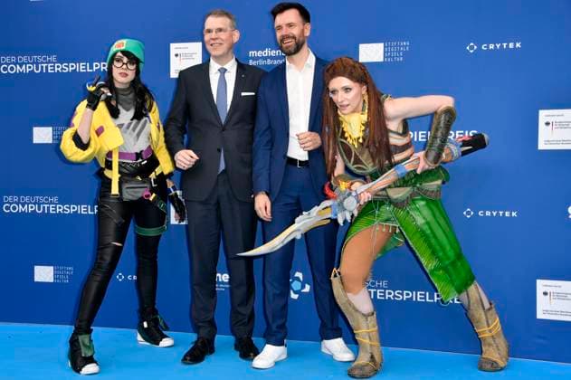 Florian Graf und Felix Falk mit den Cosplayern Killjoy und Aloy bei der Verleihung des Deutschen Computerspielpreises 2023 im Spindler & Klatt. Berlin, 11.05.2023