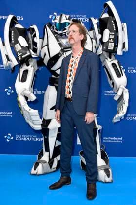 Uke Bosse mit Gamescom Bot bei der Verleihung des Deutschen Computerspielpreises 2023 im Spindler & Klatt. Berlin, 11.05.2023