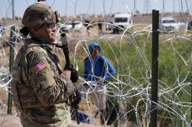 Members of the Operation Lone Star Task Force West and Texas Tactical Border Force block migrants from illegally entering Texas, May 11, 2023 near El Paso on the Rio Grande River. The units assumed blocking positions behind previously installed concertina wire in preparation for the expiration of Title 42.  WAX2023051201 MARKxOTTE