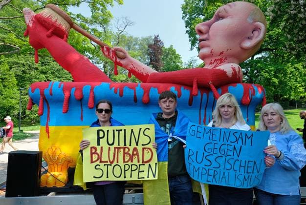 Solidaritäts-Demonstration Ukraine Aachen, 14.05.2023: Demonstration und Kundgebung zum Karlspreis 2023 an Wolodymyr Selenskyj und das ukrainische Volk. AachenStandsWithUkraine. Demonstranten vor Pappmache-Skulptur Putins Blutbad. Slogans: Gemeinsam gegen russischen Imperialismus. Putins Blutbad stoppen. Aachen Innenstadt Kurpark NRW Deutschland