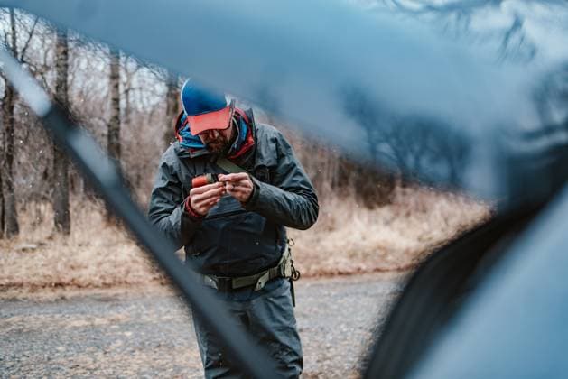 Man attaching fly to fly line in snow behind car Emigrant, Montana, United States CR_BRDO2302107A-1125084-01 ,model released, Symbolfoto