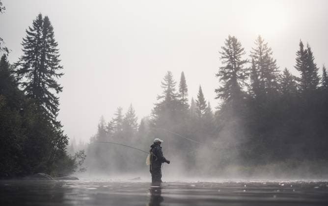 Man fly fishing in fog with trees behind him in morning Pittsburg, New Hampshire, United States CR_BRDO230211C-1125380-01 ,model released, Symbolfoto