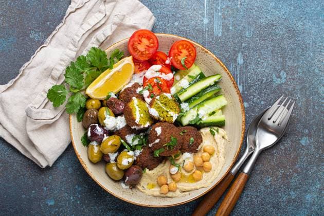 Falafel salad bowl with hummus, vegetables, olives and herbs. Vegan lunch plate top view, rustic stone background, healthy meal with falafel and veggies Falafel salad bowl with hummus, vegetables, olives, herbs and yogurt sauce. Vegan lunch plate top view on rustic stone background, healthy meal with falafel and veggies Copyright: xZoonar.com OlenaxYeromenkox 19988641