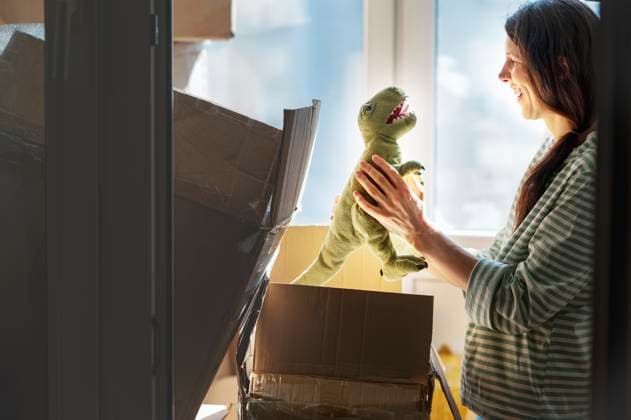 Smiling woman packing dinosaur toy in carton boxes model released, Symbolfoto, ANAF01302
