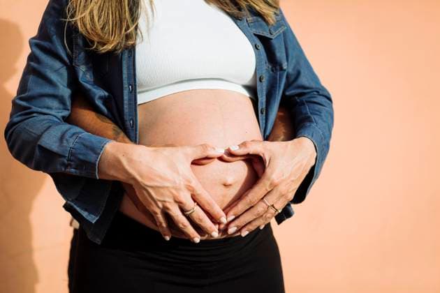 Pregnant woman making heart shape on belly with man in front of wall model released, Symbolfoto, DCRF01584