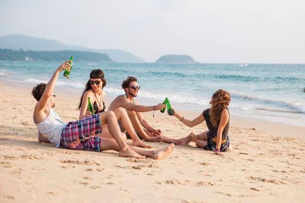 Happy friends toasting drink bottles sitting at beach model released, Symbolfoto, IKF00282