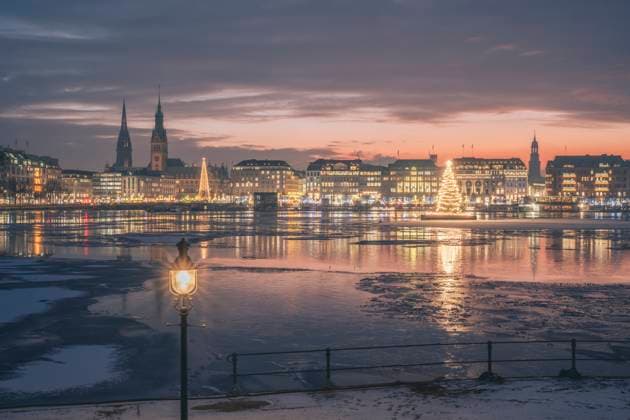 IMAGO Creative, Jahreszeit Winter in der Stadt Germany, Hamburg, Ice floating in Alster Lake at dusk with city skyline and glowing Christmas trees in background, KEBF02716