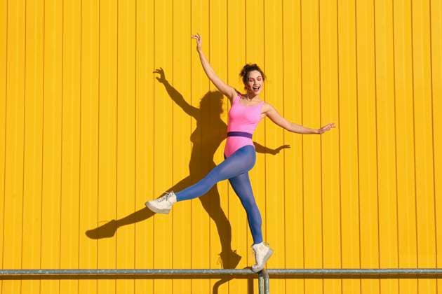 Happy woman doing ballet on railing in front of yellow wall model released, Symbolfoto, SYEF00357