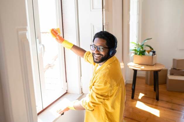 Smiling man enjoying music with headphones and cleaning window model released, Symbolfoto property released, VRAF00111