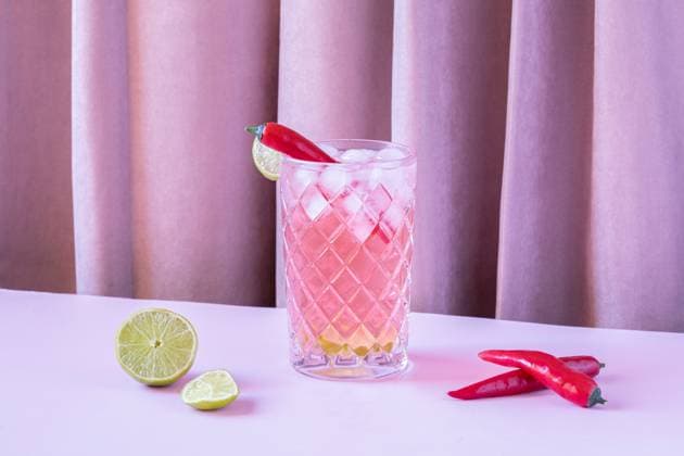Clear glass filled with chilled refreshing cocktail served with pepper and ice cubes placed on the table with lime and peppers BegoSimon_ID13908_419618_006 Copyright: xBegoxSimonx Model Released