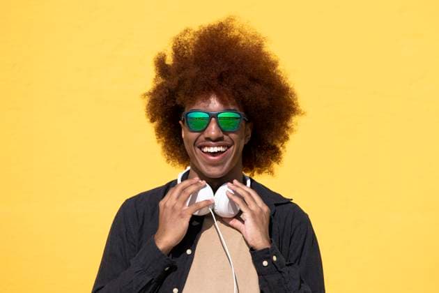 Cheerful young man wearing sunglasses and holding his headphones Barcelona, Catalonia, Spain R_ZVWBHP230524-1193441-01 ,model released, Symbolfoto