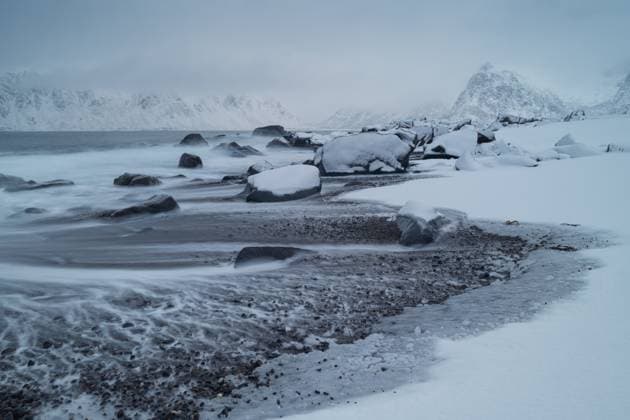 Creative Highlights World Waves recede from rocky snow covered beach, Lofoten Islands, Norway Ramberg, Nordland, Norway R_XCPU221208-1081965-01
