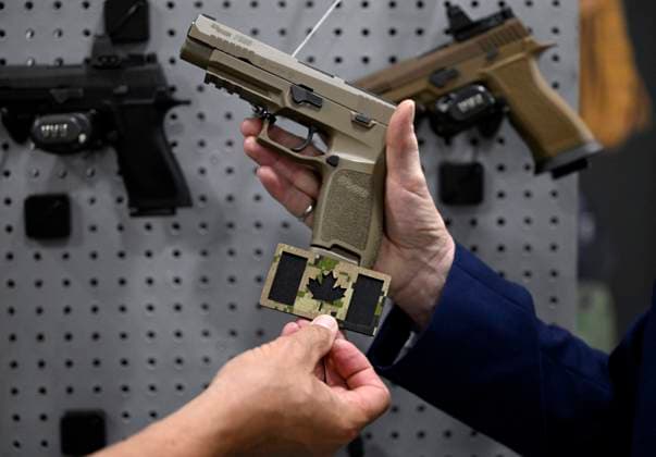 June 1, 2023, Ottawa, ON, CAN: A vendor compares the colour of a Canadian flag patch featuring the modern CADPAT camouflage design with a SIG Sauer P320, also known as the C22, that will be the new pistol for the Canadian Forces, at the CANSEC trade show, in Ottawa, on Thursday, June 1, 2023. Ottawa CAN  - ZUMAc35_ 20230601_zaf_c35_071 Copyright: xJustinxTangx