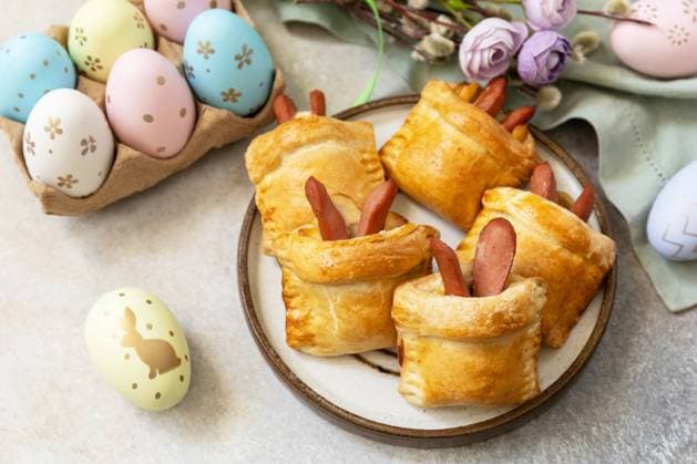 Buns in the form of an Easter rabbit from sausage and cheese in a yeast dough with colored eggs on a gray stone background. Traditional Easter symbols and food. Buns in the form of an Easter rabbit from sausage and cheese in a yeast dough with colored eggs on a gray stone background. Traditional Easter symbols and food. Copyright: xZoonar.com ELENAxHRAMOVAx 20026870
