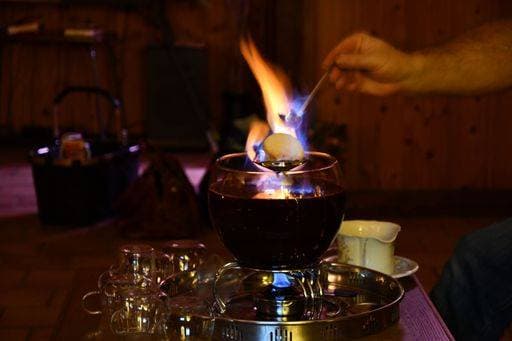 The waiter putting a burning sugarloaf over a bowl of Feuerzangenbowle on a restaurant table *** der Kellner putting einer brennend sugarloaf trueber einer Schüssel des Feuerzangenbowle am einer Gaststätte Tisch 6803780 RECORD DATE NOT STATED