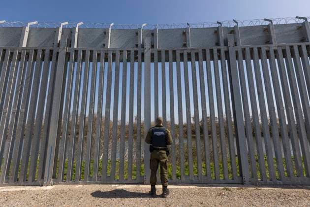 Greece Is Expanding With Concrete Filled Fence And Police Patrols The Land Borders With Turkey Border police officers stands in front of the fence searching for illegal entry. Greek border police officers patrol along the steel fence next to Evros river between Greece and Turkey to prevent unauthorized illegal entry of migrants. Greece is reinforcing the Greek side with the Turkish borders with Border Police personnel, cameras, drones, heavy vehicles, FRONTEX officers but also with a 5 meter tall fence. The fence is concrete filled, a construction which is expanding with recent announcements adding 80km more, covering the wetlands of Evros river (Meric in Turkish) and Greece s river border with Turkey. EU supported part of the border forti  Copyright: xNicolasxEconomoux originalFilename: economou-greeceis230418_npbfo.jpg