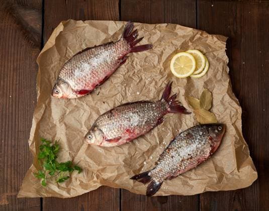 RECORD DATE NOT STATED whole fresh crucian fish with scales on a crumpled brown piece of paper, top view , 30628796.jpg, above, animal, board, brown, carp, cooking, crucian, crumpled, cuisine, delicious, diet, dinner, eating, eye, fin, fish, fishing, food, fresh, freshness, freshwater, gourmet, healthy, ingredient, kitchen, lemon, meal, meat, natural, nature, nobody, nutrition, paper, preparation, prepared, protein, raw, river, scale, spice, table, tasty, uncooked, white, whole, wooden,