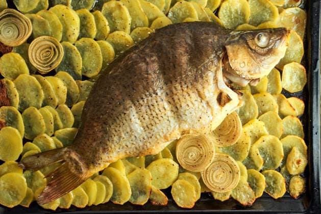 Baked carp, whole fish from the oven with sliced potatoes on a large tray. Traditional polish dish Baked carp, whole fish from the oven with sliced potatoes on a large tray. Traditional European Polish dish, suitable for a Christmas table, top view, close up Copyright: xZoonar.com NataliaxGdovskaiax 18240434