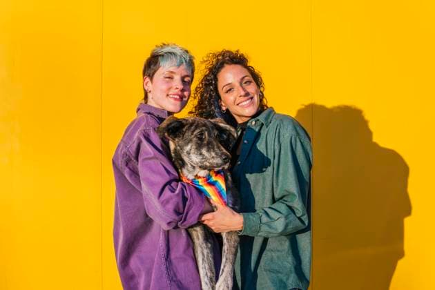 Smiling lesbian couple carrying dog in front of yellow wall model released, Symbolfoto property released, MGRF00964