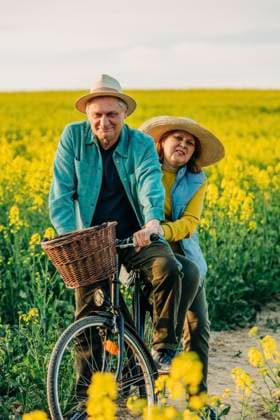 Happy senior couple riding bicycle in rapeseed field model released, Symbolfoto, VSNF00837