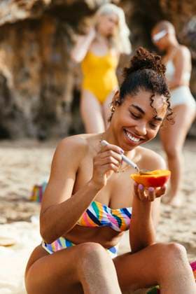 Young woman in bikini enjoying mango at beach model released, Symbolfoto, EBSF03360