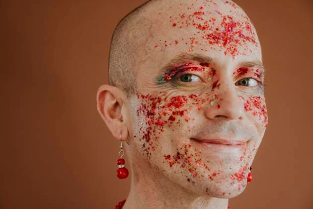 Creative Highlights Symbolbilder Smiling face of drag queen with red glitter on face against brown background model released, Symbolfoto, OSF01580