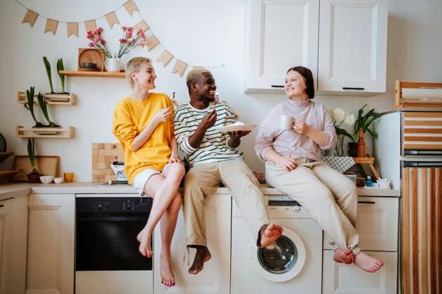 Friends enjoying breakfast sitting on kitchen counter at home model released, Symbolfoto property released, MDOF01278