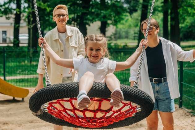 Lesbian mothers with daughter swinging swing at playground model released, Symbolfoto, VSNF01009